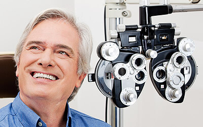Man Smiling in Front of Eye Exam Equipment